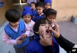 FILE - A health worker gives a polio vaccine to a child at a school in Lahore, Pakistan, Feb. 17, 2020.