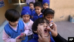 FILE - A health worker gives a polio vaccine to a child at a school in Lahore, Pakistan, Feb. 17, 2020. Polio is spreading in London, prompting Britain to launch a polio vaccine booster campaign in the capital for children younger than 10 years old.