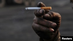 A worker smokes a cigarette during a break at a coal freight yard in Hefei