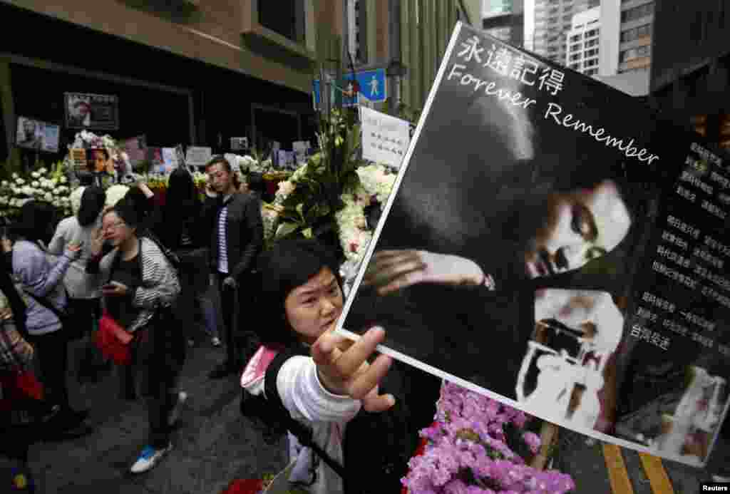 A fan adjusts a portrait of the late Hong Kong canto-pop singer and movie idol Leslie Cheung over a wreath outside the Mandarin Oriental Hotel in Hong Kong, on the eve of the 10th anniversary of his death.
