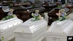 FILE - Teddy bears and flowers placed are placed on the coffins of deceased migrants inside a hangar at Lampedusa's airport, Italy, Saturday, Oct. 5, 2013.