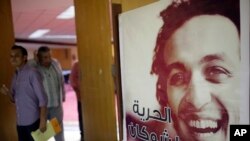 Journalists walk past a poster showing jailed Egyptian photojournalist Mahmoud Abou-Zeid, known by his nickname Shawkan at the press syndicate in Cairo, Egypt, Aug. 12, 2015. He's been locked up without any charges for covering the Rabaa massacre in Cairo on Aug. 14, 2013. 
