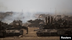 Israeli soldiers stand atop a tank at a staging area near the border with the Gaza Strip, July 13, 2014. 