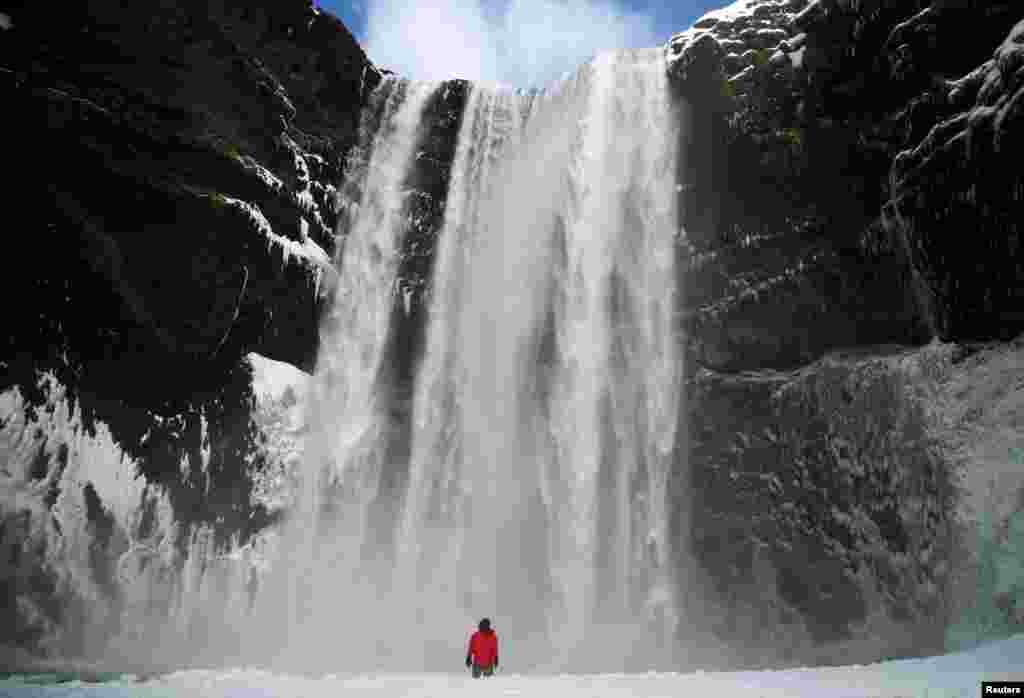 A man stands in front of the Skogafoss waterfall in Skogar, Iceland, March 8, 2020.