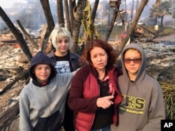Lisa Kermode, second from right, and her children, from left, Damien, Lola and Michael, stand outside the ruins of their home after a wildfire swept through Ventura, Calif., Dec. 5, 2017. They were home Monday night when Lisa started to smell smoke and her phone buzzed with an alert, urging residents to evacuate. "Within an hour, it was here," she said. "We left. We grabbed nothing," she said Tuesday. "We lost everything."