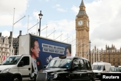 An advertising van with images of Britain's Prime Minister David Cameron and leader of the opposition Labour Party Ed Miliband drives around Parlaiment Square, central London, Britain, May 7, 2015. REUTERS/Phil Noble - RTX1BXSZ