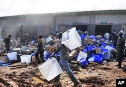 Guinean soldiers remove boxes filled with electoral materials from a warehouse on fire in a military camp in Conakry, 16 Sep 2010