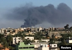 FILE - Smoke rises during a fight between members of the Libyan internationally recognized government forces and Eastern forces in Ain Zara, Tripoli, Libya, May 5, 2019.