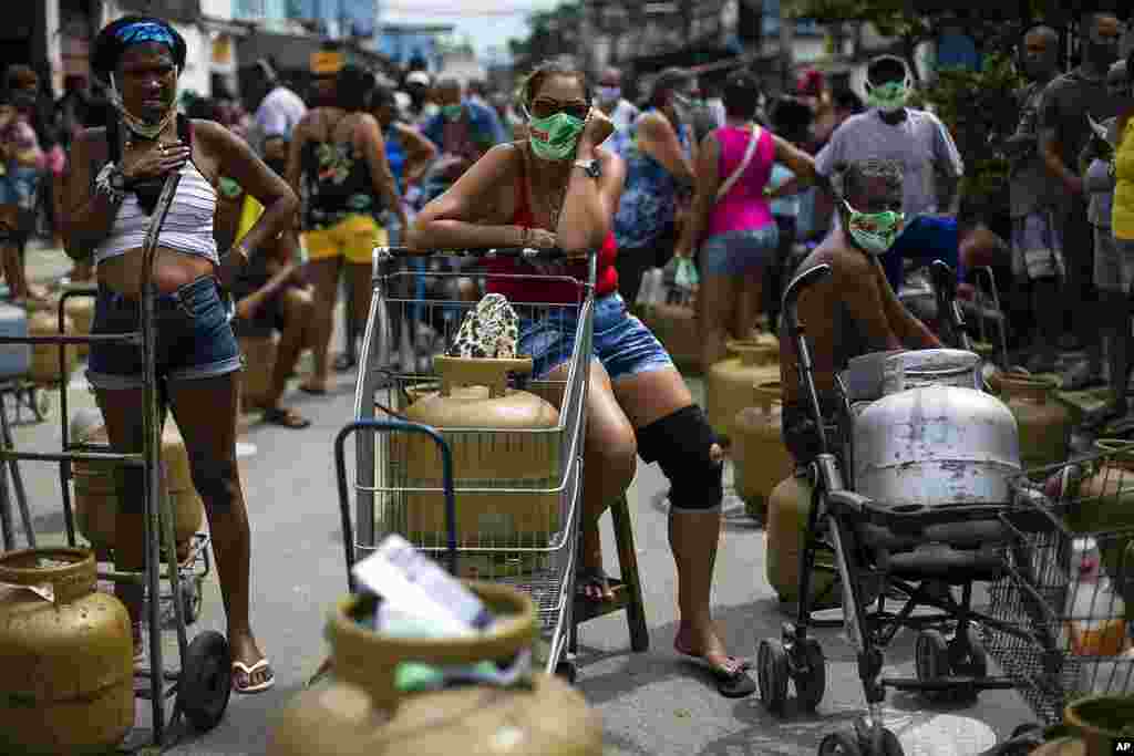 People wearing masks amid the COVID-19 pandemic wait to buy low-cost cooking gas from the Petrobr&#225;s Oil Tankers Union in the Vila Vintem favela of Rio de Janeiro, Brazil.