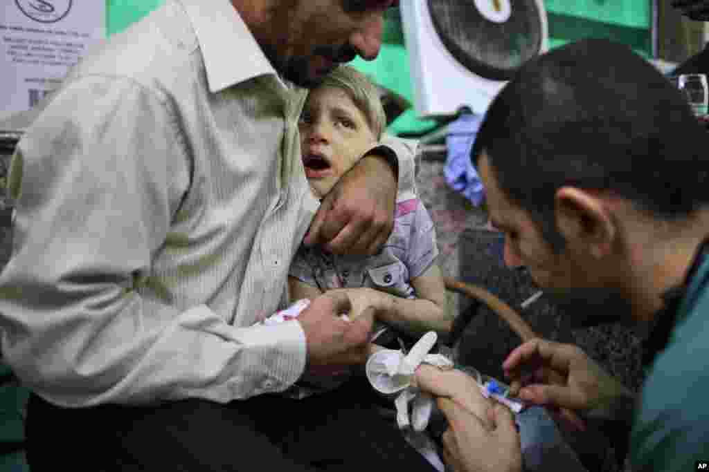 A Syrian child reacts while being treated by a doctor, in a hospital in Aleppo, Syria, September 11, 2012. 