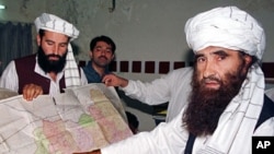 A 2001 file photo of Jalaluddin Haqqani (R), Leader of the Haqqani Network, pointing to a map of Afghanistan during a visit to Islamabad, Pakistan while his son Naziruddin (L) looks on