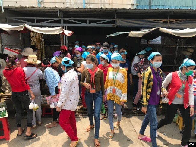 Garment factory workers wear face masks while on a lunch break near Propitious (Cambodia) Garment Ltd factory, in Kandal province, Cambodia, March 20, 2020. (Kann Vicheika/VOA Khmer)