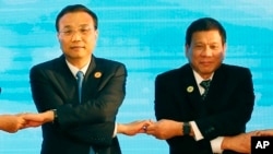 FILE - In this Sept. 7, 2016, photo, Chinese Premier Li Keqiang (L) and Philippine President Rodrigo Duterte link arms during the ASEAN Plus Three summit in Vientiane, Laos. After lashing out at longtime ally America, Duterte is making a state visit to Ch