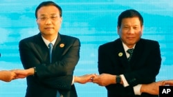 FILE - In this Sept. 7, 2016, photo, Chinese Premier Li Keqiang (L) and Philippine President Rodrigo Duterte link arms during an ASEAN summit in Vientiane, Laos. After lashing out at longtime ally America, Duterte is making a state visit to China in an apparent charm offensive.
