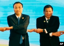 FILE - In this Sept. 7, 2016, photo, Chinese Premier Li Keqiang (L) and Philippine President Rodrigo Duterte link arms during the ASEAN Plus Three summit in Vientiane, Laos. After lashing out at longtime ally America, Duterte is making a state visit to Ch