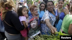Supporters of Venezuela's President Nicolas Maduro place flowers in front of portraits of Venezuela's late president, Hugo Chavez, at the Plaza Bolivar near the building housing the National Assembly in Caracas, Jan. 7, 2016.