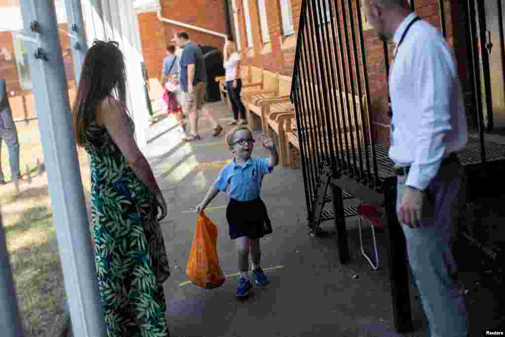 A student waves to his teachers as he arrives at St Dunstan&#39;s College junior school, as some schools re-open following the outbreak of COVID-19, in London, Britain.