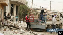 In this photo provided Jan. 4, 2018, by the Syrian anti-government activist group, Edlib Media Center, EMC, which has been authenticated based on its contents and other AP reporting, shows Syrian citizens load their belongings at a pickup, as they flee their house which was attacked by Russian airstrikes, in Tel al-Toukan village, eastern Idlib province, Syria.