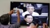 FILE - Journalists take photographs of a television screen showing the trial of Kaing Guek Eav, alias Duch, former chief of the S-21 prison, at the Extraordinary Chambers in the Courts of Cambodia (ECCC) on the outskirts of Phnom Penh, Feb. 3, 2012.