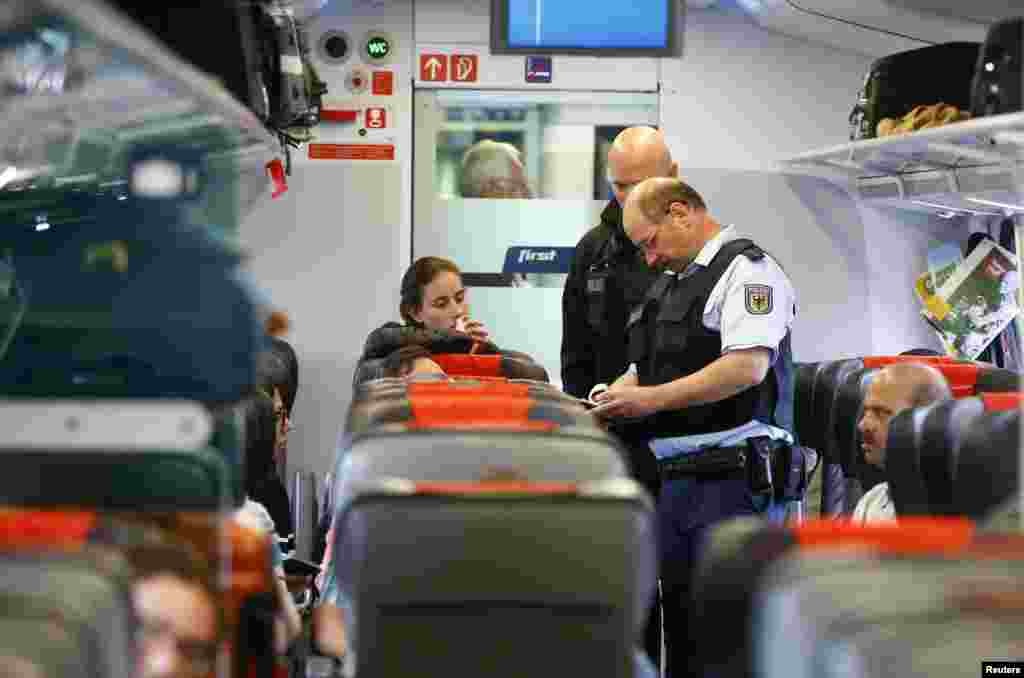 German policemen check passenger&#39;s documents on a train in Freilassing, on the border between Austria and Germany. The German government is sticking with its forecast for 800,000 asylum seekers and refugees to arrive in the country this year despite strong inflows in recent weeks, a spokesman for the Interior Ministry said.