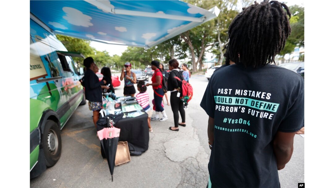 People gather around the Ben & Jerry's "Yes on 4" truck as they learn about Amendment 4 and eat free ice cream at Charles Hadley Park in Miami, Oct. 22, 2018.