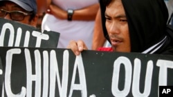 FILE - Protesters hold placards during a rally outside the Chinese Consulate in Manila to protest China's artificial island-building at the disputed islands, reefs and shoals off South China Sea.