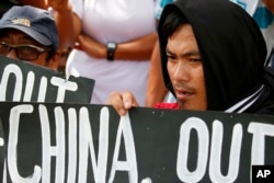 FILE - Protesters hold placards during a rally outside the Chinese Consulate in Manila to protest China's artificial island-building at the disputed islands, reefs and shoals off South China Sea.