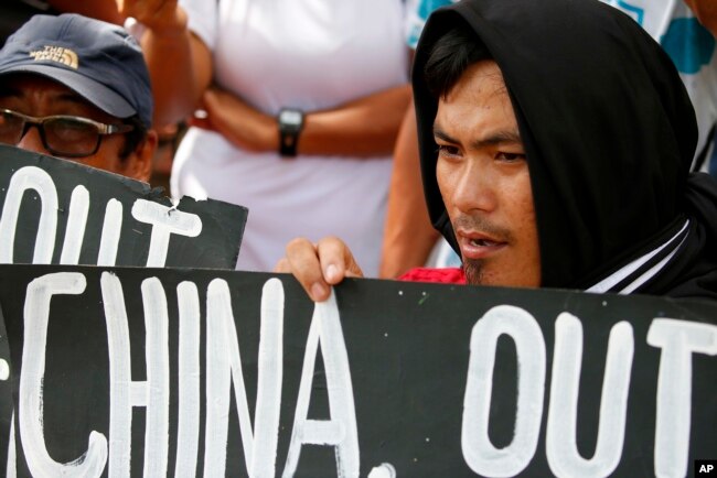 FILE - Protesters hold placards during a rally outside the Chinese Consulate in Manila to protest China's artificial island-building at the disputed islands, reefs and shoals off South China Sea.