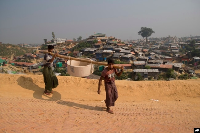 Rohingya refugees carry a hume pipe in Balukhali refugee camp near Cox's Bazar, in Bangladesh, Nov. 17, 2018.