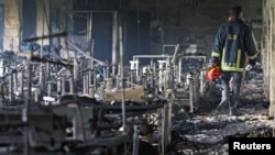 一消防队员检查在孟加拉首都达卡郊区工业区一家失火制衣厂现场