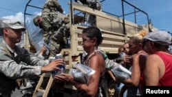 Soldiers of Puerto Rico's national guard distribute relief items to people, after the area was hit by Hurricane Maria in San Juan, Puerto Rico, Sept, 24, 2017. 