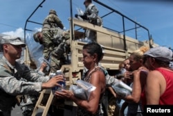 Soldiers of Puerto Rico's national guard distribute relief items to people, after the area was hit by Hurricane Maria in San Juan, Puerto Rico, Sept, 24, 2017.