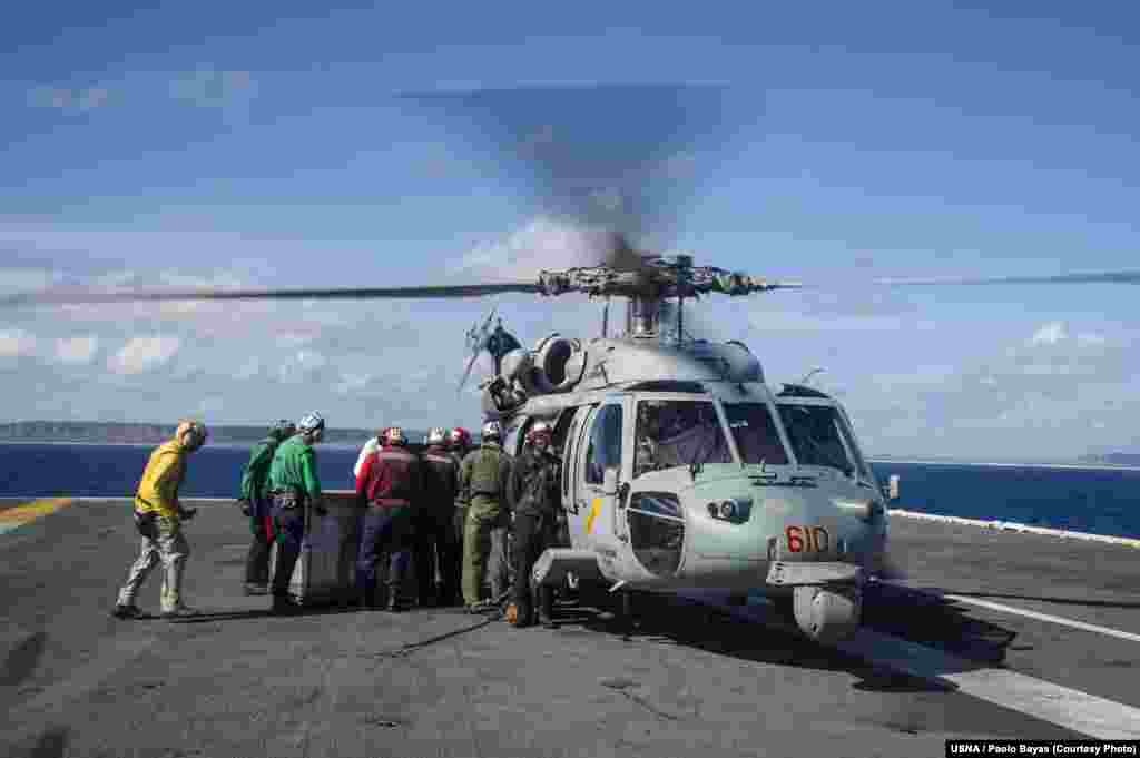 Sailors aboard the U.S. Navy&#39;s forward-deployed aircraft carrier USS George Washington load containers of water onto an MH-60S Seahawk, Nov. 15, 2013. (U.S. Navy)