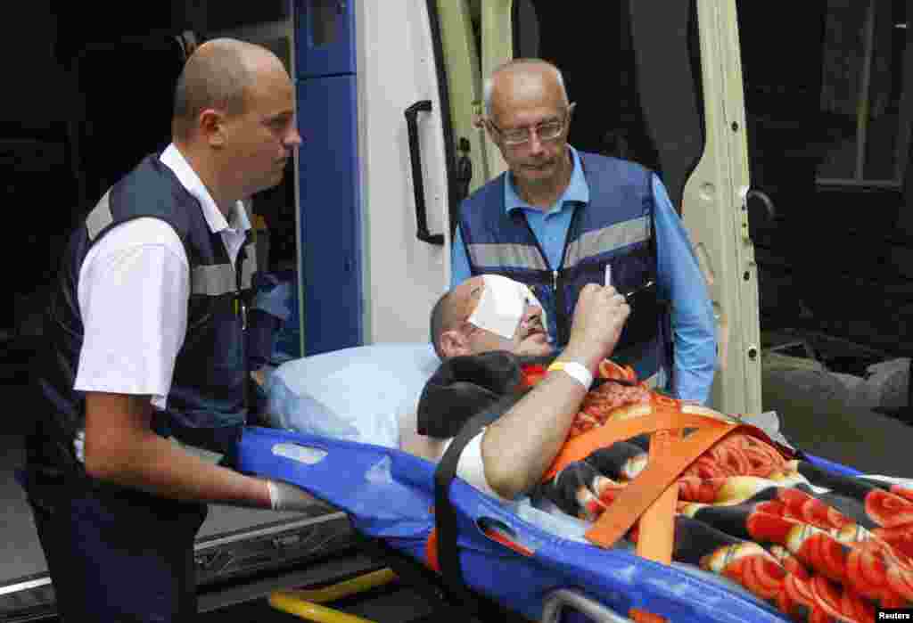 An injured Ukrainian serviceman smokes as medical personnel help him into an ambulance at the military hospital in Kyiv, Sept. 2, 2014.