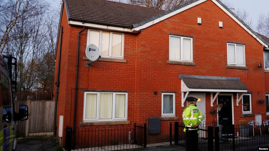 Police officers stand outside a house being searched in connection to a stabbing at Victoria Station in Manchester, Britain, Jan. 1, 2019. 