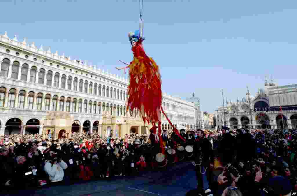 이탈리아 베니스 카니발이 열린 성 마르코 광장에서 화려한 전통 의상을 입은 여성이 공중에 매달린 채 &#39;천사의 비상&#39; 공연을 펼치고 있다.