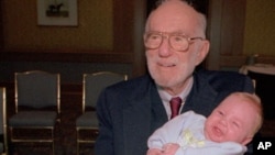 Dr. Spock, 90, holds a baby at a Boston baby fair in April 1993.