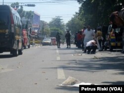 Polisi mensterilkan jalanan yang diduga terdapat serpihan tubuh korban ledakan bom di sekitar Gereja Katolik Santa Maria Tak Bercela di Surabaya, 13 Mei 2018. (Foto: VOA/Petrus Riski)