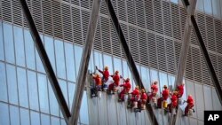 2018年8月31日，中国中央电视台（CCTV）总部大楼外面，悬挂在绳索上的工人擦玻璃。