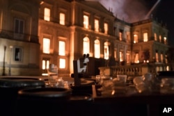 Salvaged equipment lies on the ground as flames engulf the 200-year-old National Museum of Brazil, in Rio de Janeiro, Sept. 2, 2018.