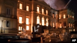 Salvaged equipment lies on the ground as flames engulf the 200-year-old National Museum of Brazil, in Rio de Janeiro, Sept. 2, 2018.