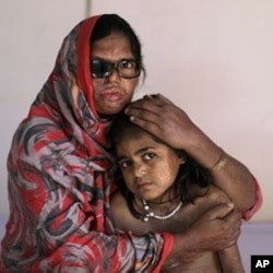 Pakistani acid attack survivor, Azim Mai, 35, holds her daughter Shaziya, 8, while sitting on a bed waiting to have a massage session for their wounds, at the Acid Survivors Foundation (ASF) in Islamabad, Pakistan, December 13, 2011.