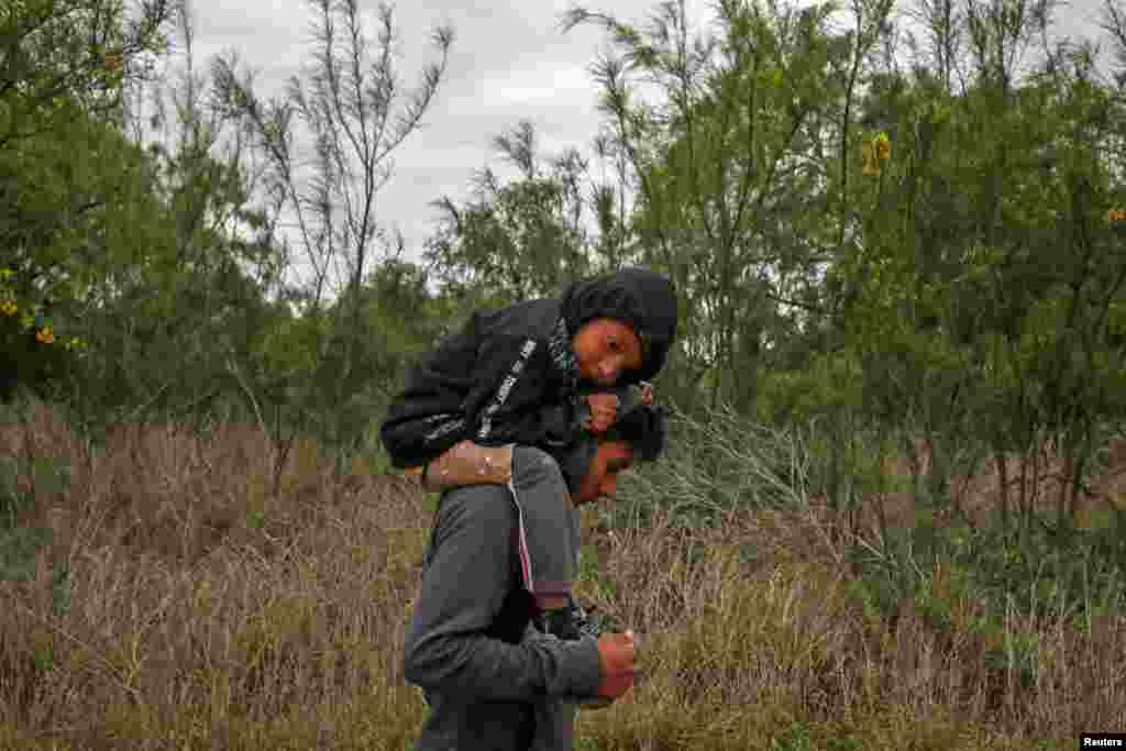 Ostavio, a five-year-old boy from Guatemala, rests on the shoulders of his brother Eduardo as they walk through a field after illegally crossing the Rio Grande river into the United States from Mexico, in Penitas, Texas, March 31, 2019.