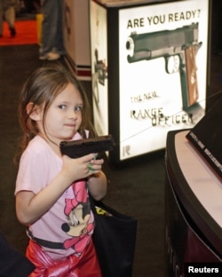 A young attendee tries out a pistol during the National Rifle Association's (NRA) 141st Annual Meetings & Exhibits in St. Louis, Missouri, April 13, 2012.