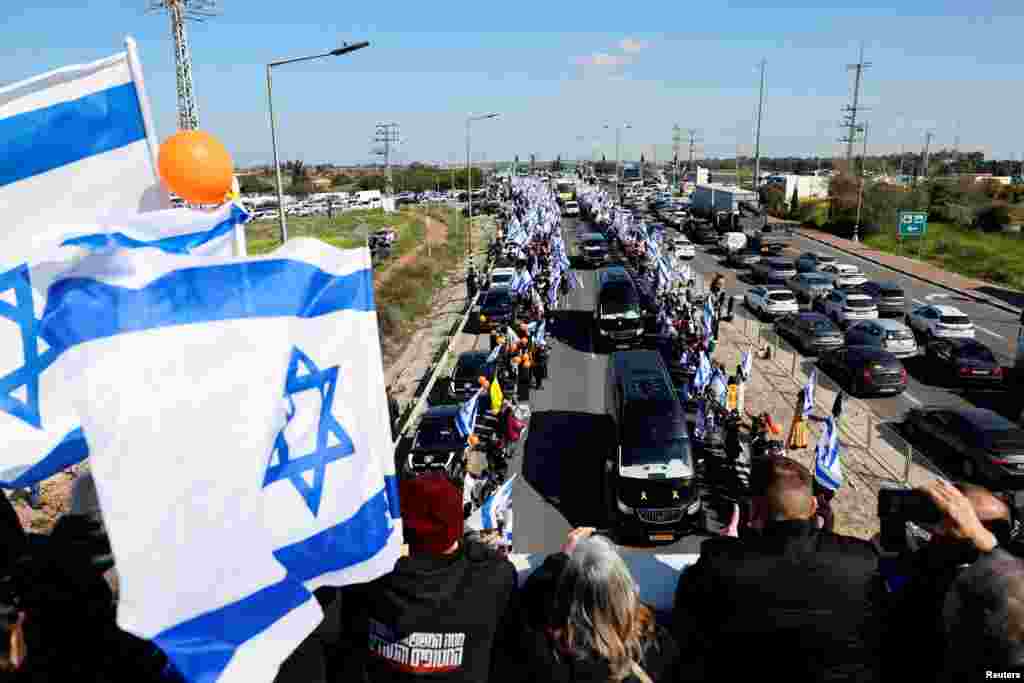 Israelis gather as a convoy carrying the coffins of Shiri, 32, and her two children Kfir, 9 months old, and Ariel, 4, of the Bibas family, who were kidnapped from their home in Kibbutz Nir Oz during the deadly Oct. 7, 2023 attack by Hamas and then killed in Gaza, makes its way as part of the funeral procession in Ashkelon.