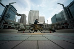 A man with a protective mask rides a bicycle at usually crowded street at lunch time at Tokyo's Shinjuku district, April 17, 2020.