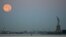 A full moon, known as the Blue Moon, is seen next to the Statue of Liberty in New York. The Blue Moon effect refers to the second full moon in a calendar month.