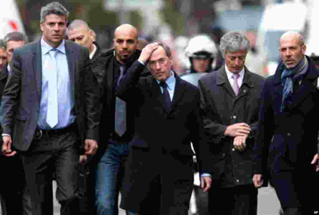 French Interior Minister Claude Gueant, center, is surrounded by police chiefs and aides as he arrive to talk to the media near an apartment where an Islamic extremist was holed up, in Toulouse, France Thursday, March 22, 2012. Mohamed Merah, who boasted 