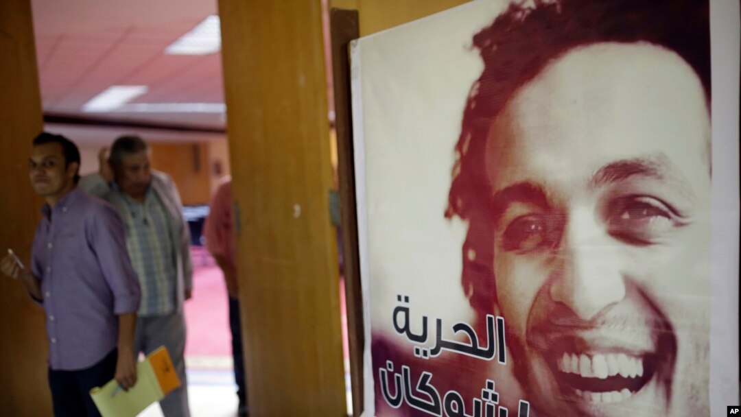Para wartawan berjalan melewati sebuah poster yang menampilkan jurnalis foto Mesir Mahmoud Abou-Zeid, yang dikenal dengan julukan Shawkan di Kairo, Mesir, 12 Agustus 2015. Dia ditahan tanpa tuduhan saat meliput pembantaian Rabaa di Kairo.