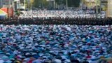Muslim men, bowing toward Mecca, offer Eid al-Fitr prayers that marks the end of the holy fasting month of Ramadan as police guard them at the main mosque in Moscow, Russia.